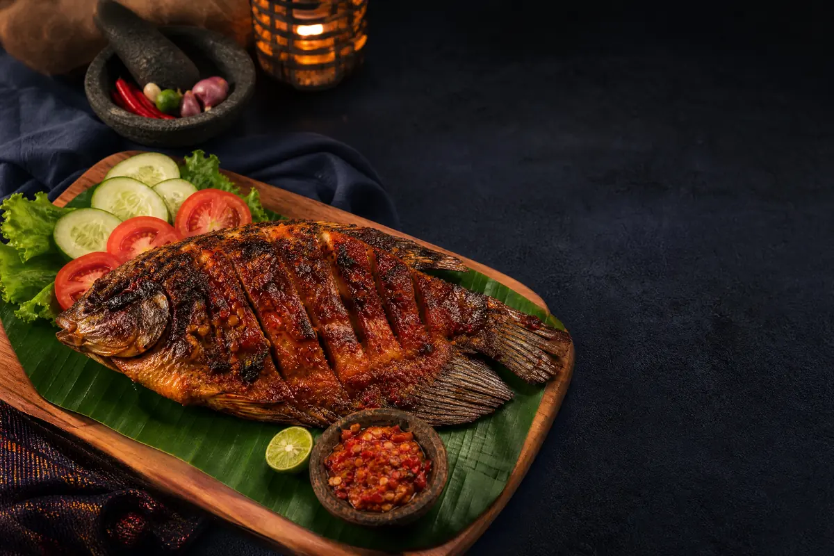 Gurame bakar dengan sambal, sayuran, dan jeruk nipis